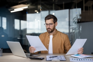 Male M&A Buyer Reviewing Financial Documents